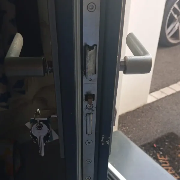 Crémone multipoints remplacée sur une porte d'entrée en aluminium, têtière et pênes visibles, TD Serrurerie