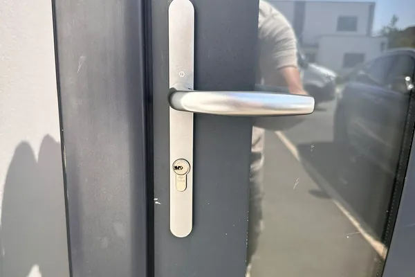 Cylindre Cisa et poignée sur plaque posés sur une porte d'entrée aluminium anthracite, TD Serrurerie